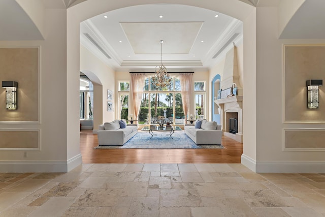 living room with a raised ceiling, ornamental molding, a high ceiling, and a notable chandelier