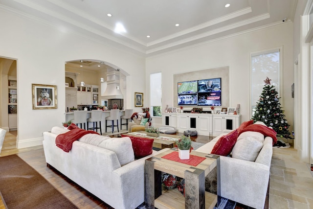 living room featuring a tray ceiling, crown molding, plenty of natural light, and a towering ceiling