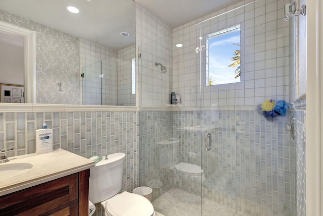 bathroom featuring vanity, toilet, tile walls, and a shower with shower door