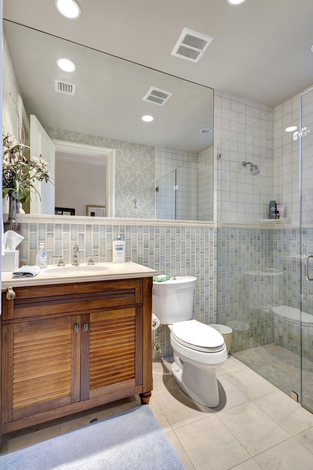 bathroom featuring walk in shower, tile patterned flooring, toilet, vanity, and tile walls