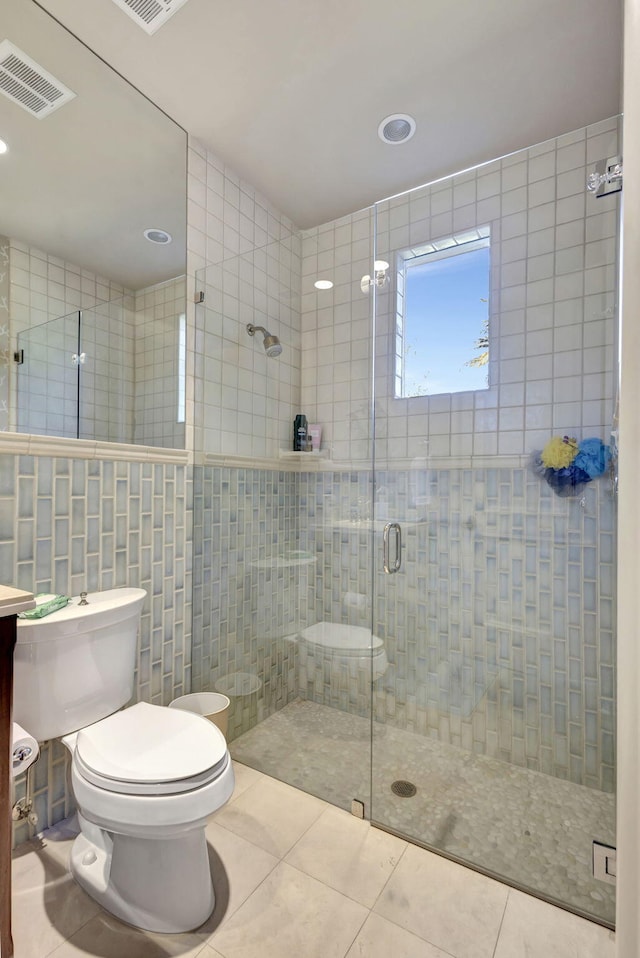 bathroom with tile walls, tile patterned flooring, an enclosed shower, and toilet