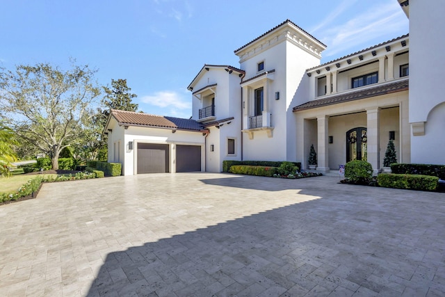 mediterranean / spanish home featuring a garage, a balcony, and french doors