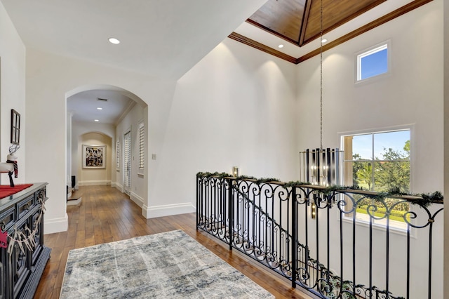 hallway with a chandelier, crown molding, dark wood-type flooring, and a high ceiling