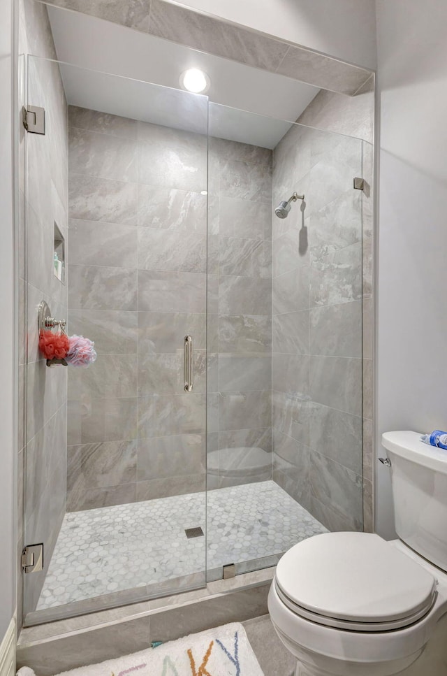 bathroom with tile patterned floors, a shower with shower door, and toilet