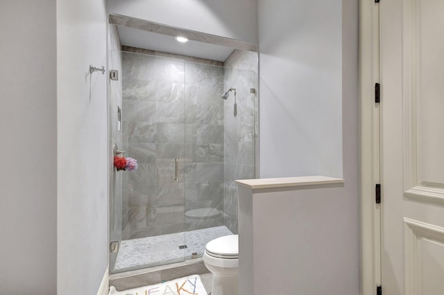 bathroom with a shower with door and toilet