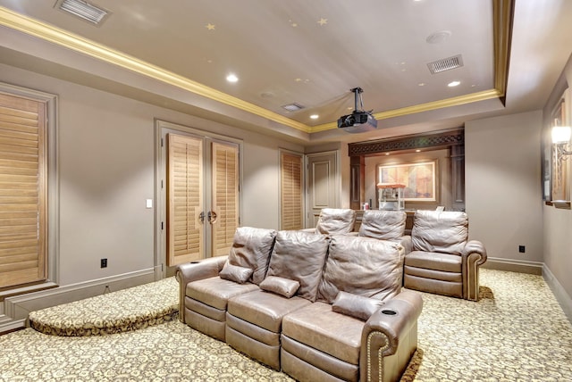 home theater room with a raised ceiling, carpet floors, crown molding, and french doors