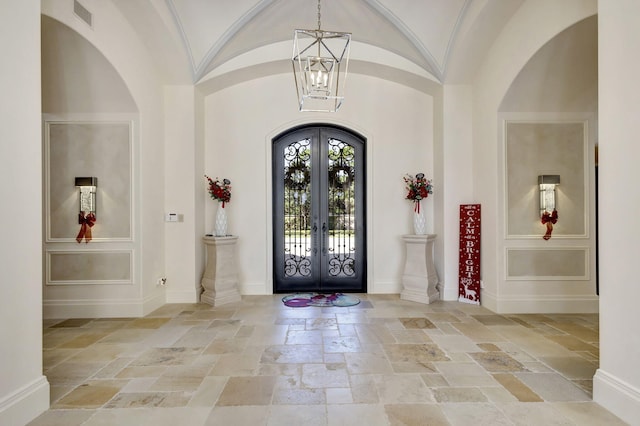 foyer featuring an inviting chandelier, lofted ceiling, and french doors