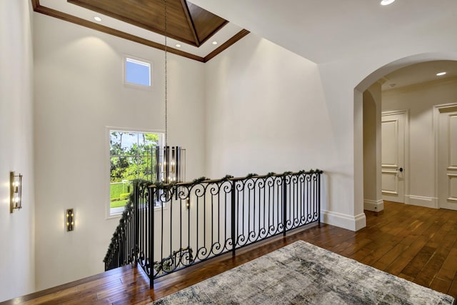 corridor featuring a chandelier, a high ceiling, dark hardwood / wood-style floors, and ornamental molding