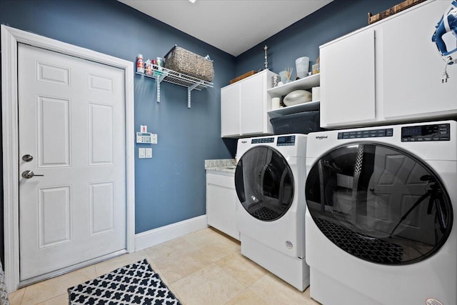 washroom featuring cabinets, light tile patterned floors, and washer and clothes dryer