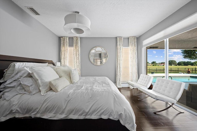 bedroom with a textured ceiling, dark hardwood / wood-style floors, and access to outside