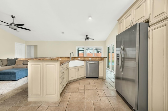 kitchen featuring lofted ceiling, sink, cream cabinetry, and appliances with stainless steel finishes