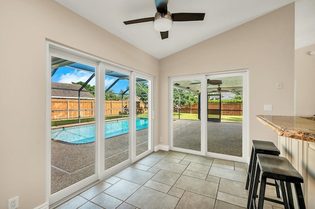 doorway featuring ceiling fan, light tile patterned flooring, and lofted ceiling