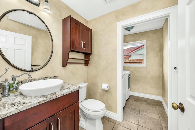 bathroom featuring toilet, washer and dryer, and vanity