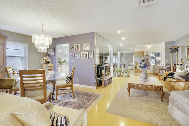 living room with a textured ceiling, light hardwood / wood-style floors, and a notable chandelier