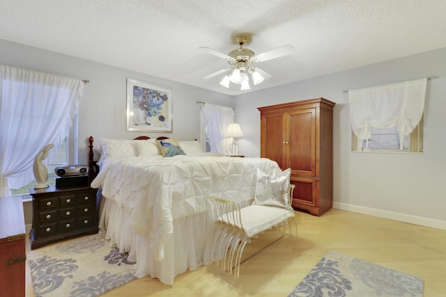 bedroom featuring a textured ceiling, light wood-type flooring, and ceiling fan