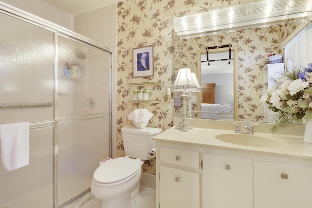 bathroom with vanity, toilet, and a shower with door