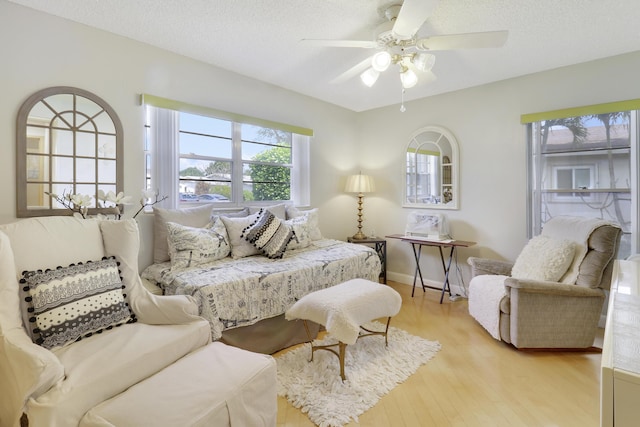 bedroom with ceiling fan, light hardwood / wood-style floors, and a textured ceiling