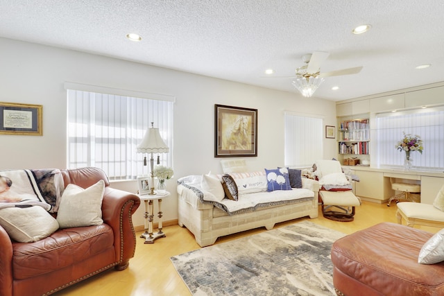 living room with a textured ceiling, light hardwood / wood-style floors, and ceiling fan