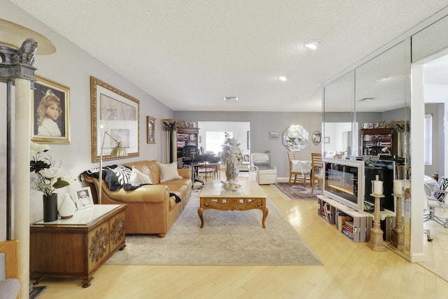 living room with light wood-type flooring and a textured ceiling