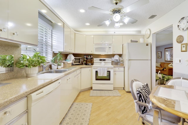 kitchen with a textured ceiling, white appliances, sink, and light hardwood / wood-style flooring