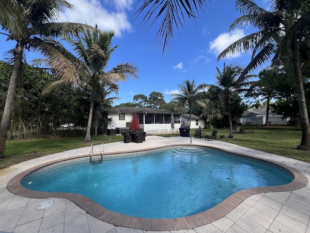 view of pool with a sunroom, a yard, and a patio