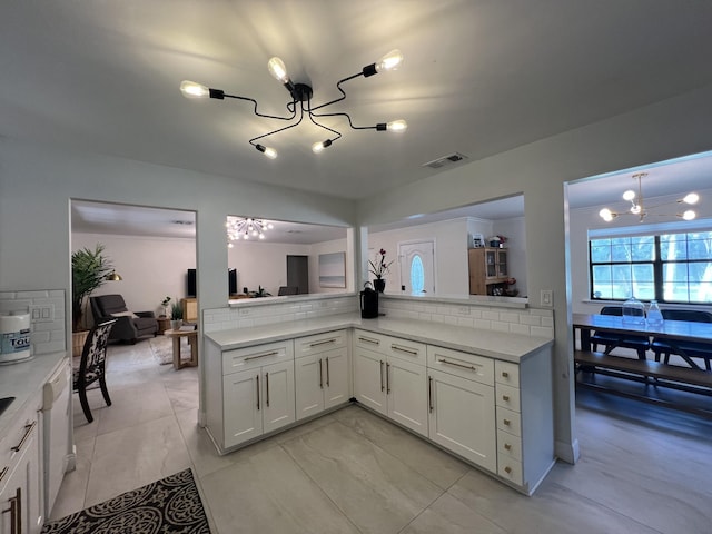 kitchen with white cabinets, tasteful backsplash, a notable chandelier, light tile patterned flooring, and kitchen peninsula