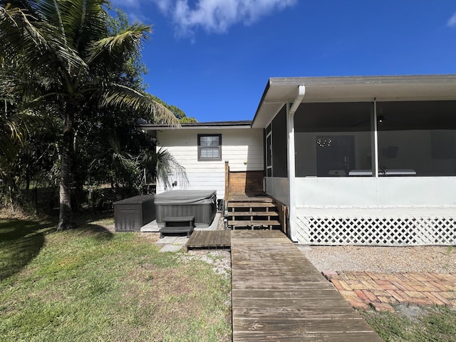 back of property featuring a yard, a hot tub, and a sunroom