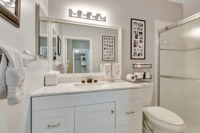 bathroom with vanity, a shower with shower door, and toilet