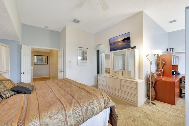 bedroom with light carpet, a textured ceiling, and ceiling fan