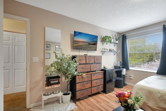 bedroom with hardwood / wood-style floors, a textured ceiling, and a closet