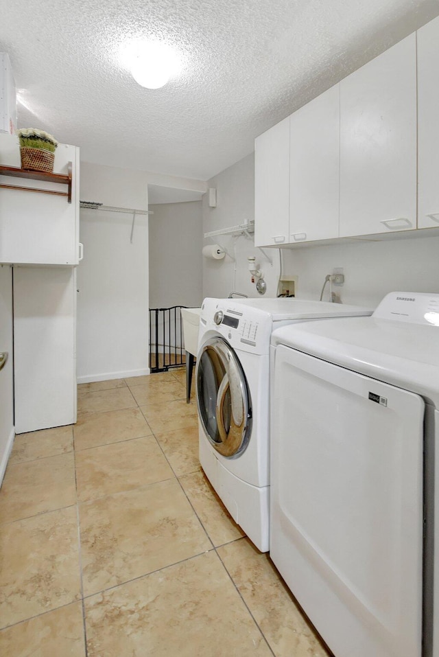 laundry area with light tile patterned floors, cabinets, a textured ceiling, and independent washer and dryer