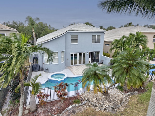 rear view of property with a patio and a pool with hot tub