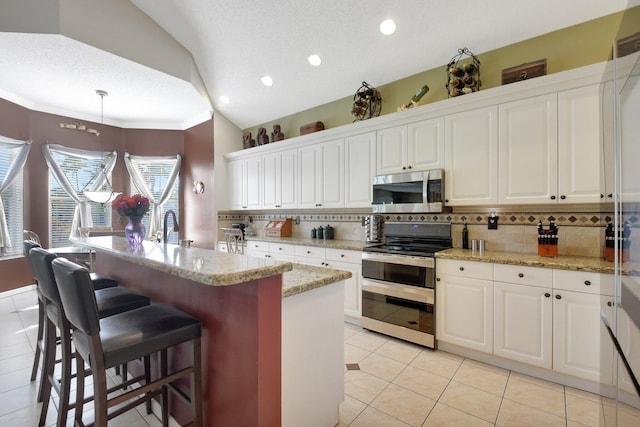 kitchen featuring white cabinetry, lofted ceiling, appliances with stainless steel finishes, and tasteful backsplash