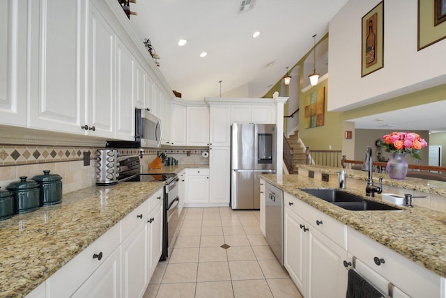 kitchen with lofted ceiling, sink, appliances with stainless steel finishes, decorative light fixtures, and white cabinetry