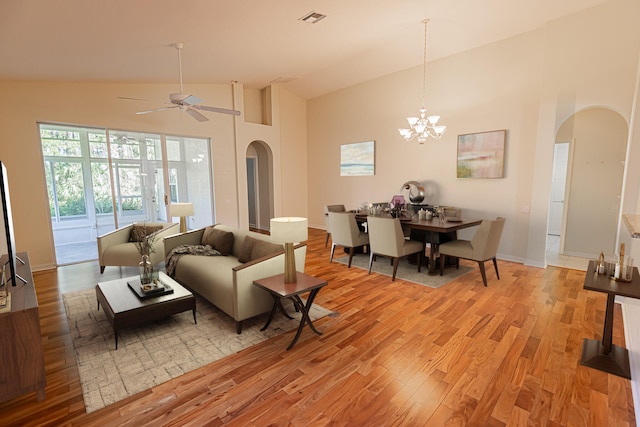 living room featuring ceiling fan with notable chandelier, light hardwood / wood-style flooring, and high vaulted ceiling