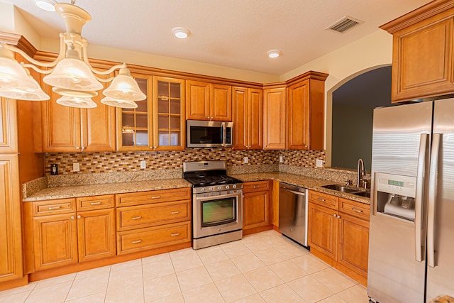 kitchen with light tile patterned flooring, appliances with stainless steel finishes, sink, and decorative light fixtures