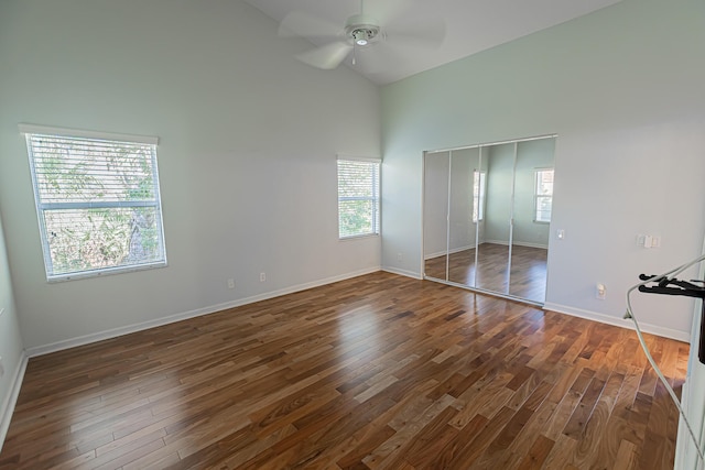 unfurnished bedroom with dark hardwood / wood-style flooring, high vaulted ceiling, a closet, and ceiling fan