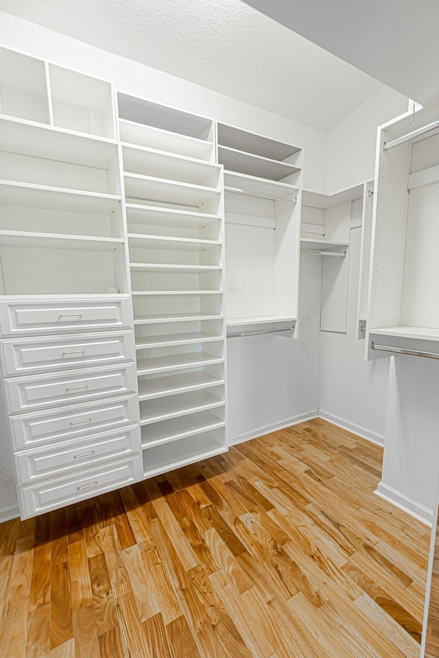 walk in closet with light hardwood / wood-style floors