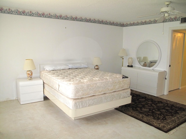 bedroom with ceiling fan and a textured ceiling