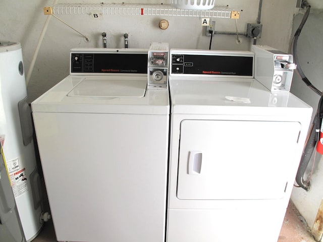 clothes washing area featuring water heater and washer and clothes dryer