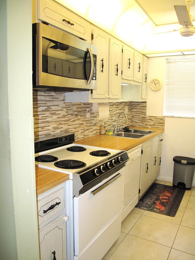 kitchen with white appliances, sink, decorative backsplash, light tile patterned flooring, and white cabinetry