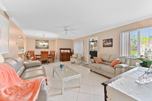 living area featuring arched walkways, light tile patterned flooring, ceiling fan with notable chandelier, baseboards, and crown molding