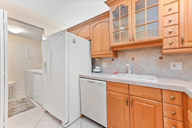 kitchen with white appliances, sink, washing machine and dryer, light tile patterned floors, and tasteful backsplash