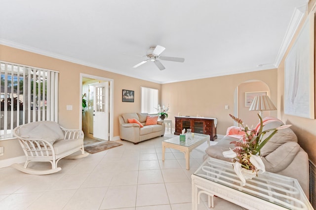 living room with light tile patterned floors, ceiling fan, arched walkways, ornamental molding, and plenty of natural light