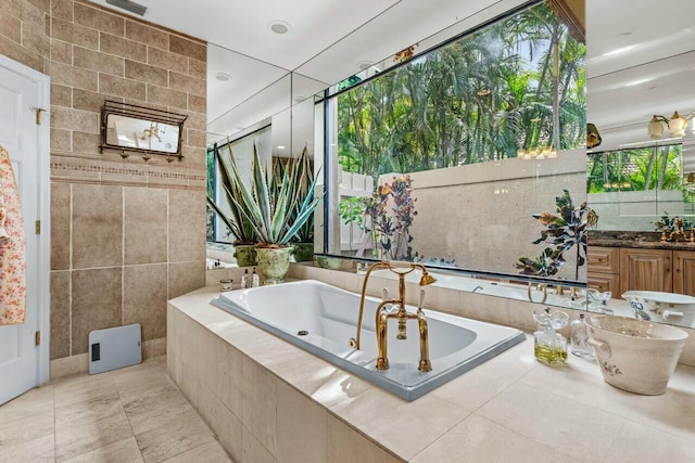 bathroom with tile patterned floors, vanity, tile walls, and tiled tub