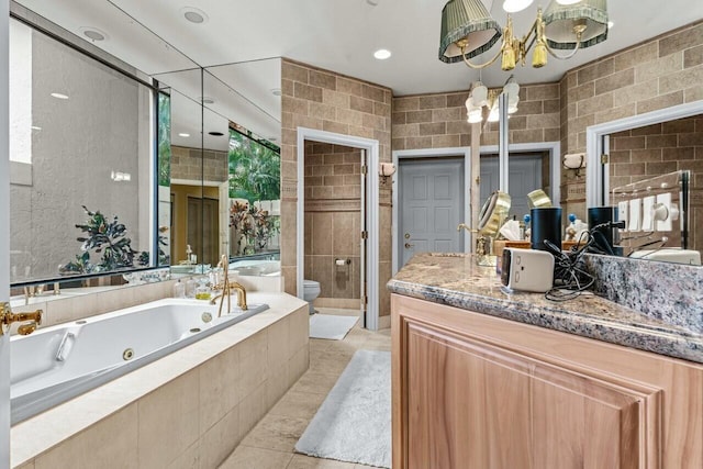 bathroom with tile walls, tile patterned flooring, vanity, toilet, and tiled tub