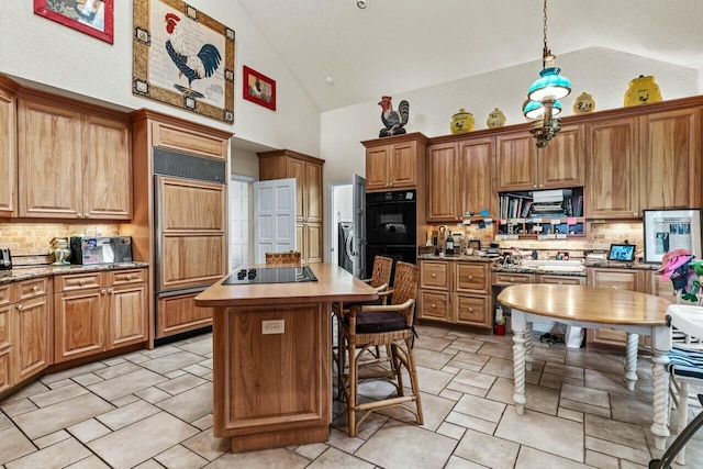 kitchen featuring tasteful backsplash, hanging light fixtures, black appliances, and a center island