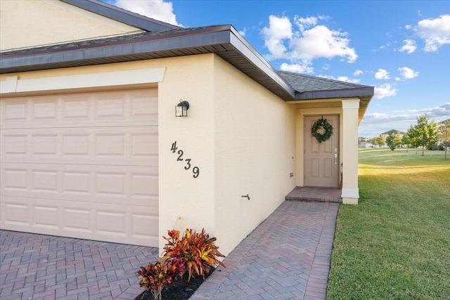 view of exterior entry featuring a lawn and a garage