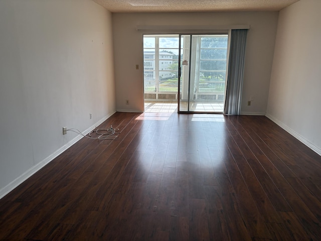 unfurnished room with dark hardwood / wood-style floors and a textured ceiling