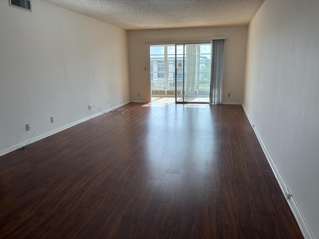 unfurnished room with dark hardwood / wood-style flooring and a textured ceiling